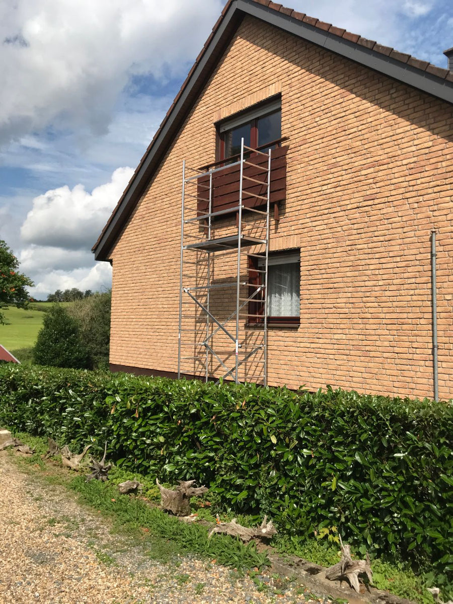 Giebelwand vor dem Umbau: alte Holzbrüstung am Dachfenster, davor ein Fahrgerüst