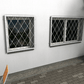 Zwei Fenstergitter aus feuerverzinktem Stahl mit Rautenmuster als Einbruchschutz an einer Hausfassade