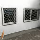 Zwei Fenstergitter aus feuerverzinktem Stahl mit dekorativem Ornamentmuster als Einbruchschutz an einer Hausfassade